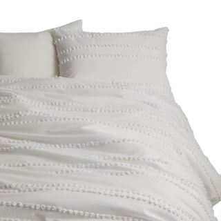 A white comforter bedding set with pom poms