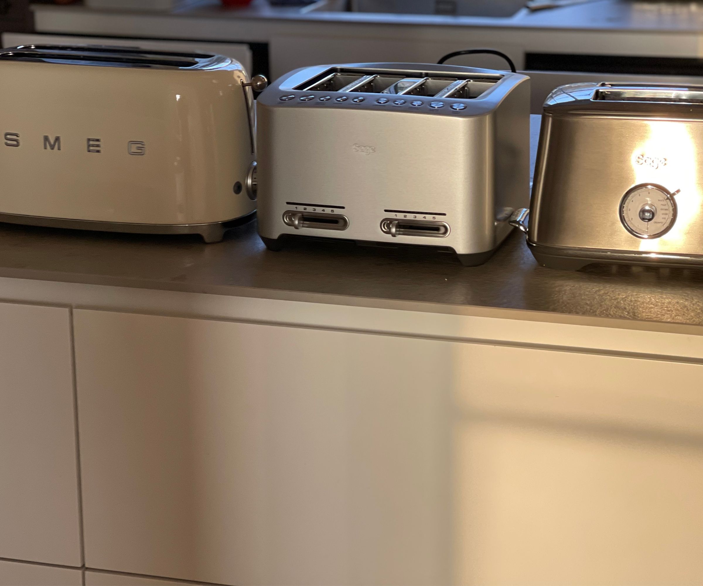 The Smeg toaster next to two Breville toasters on the countertop