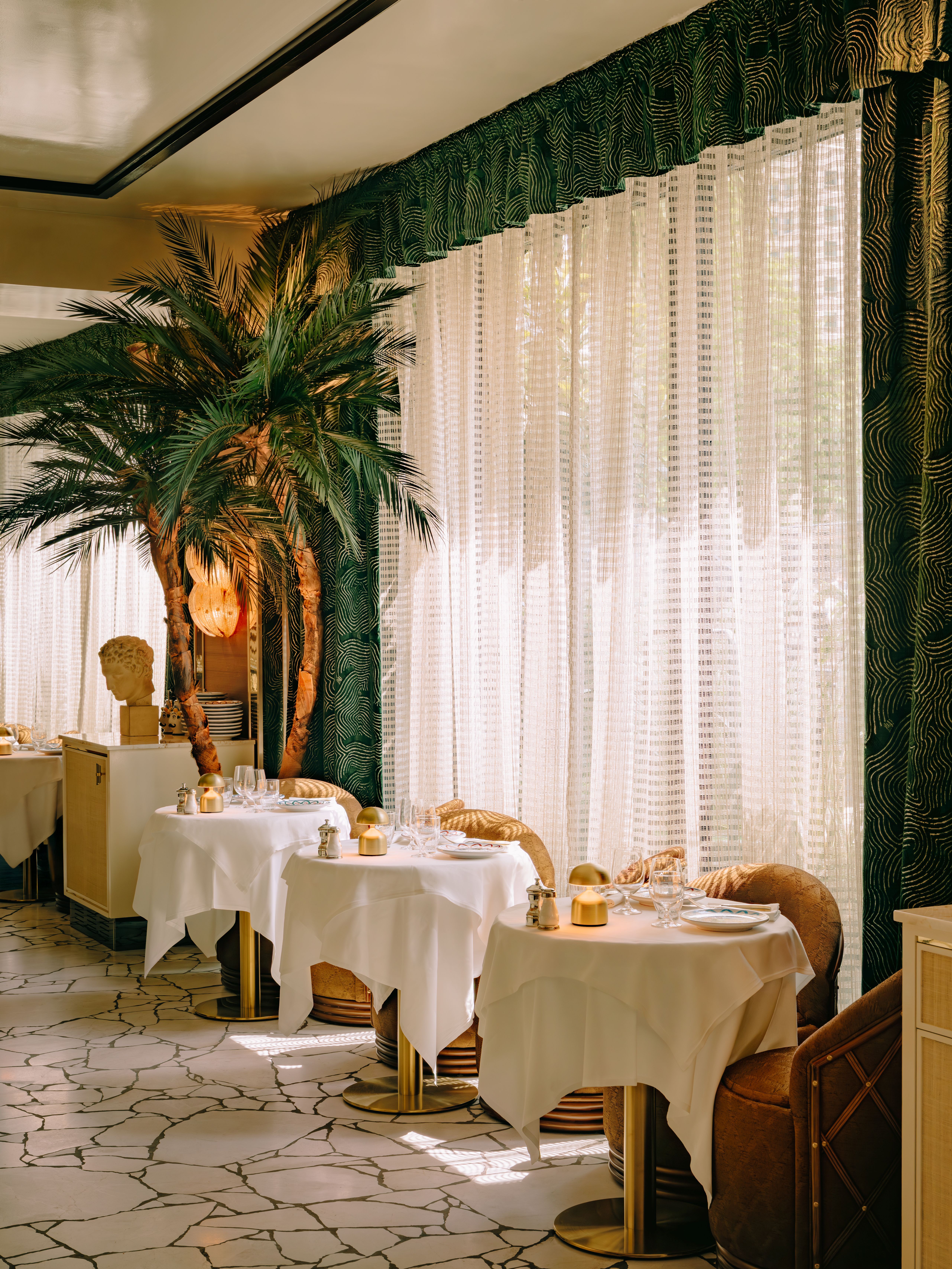 Interiors of Barbarella restaurant, with 1970s-inspired decor, reflective walls, and lots of contrasting textures and motifs, along with palm plants.