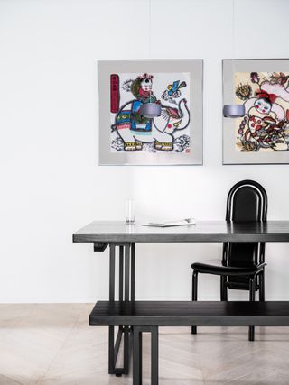 black dining table and chair, white walls and colorful artwork