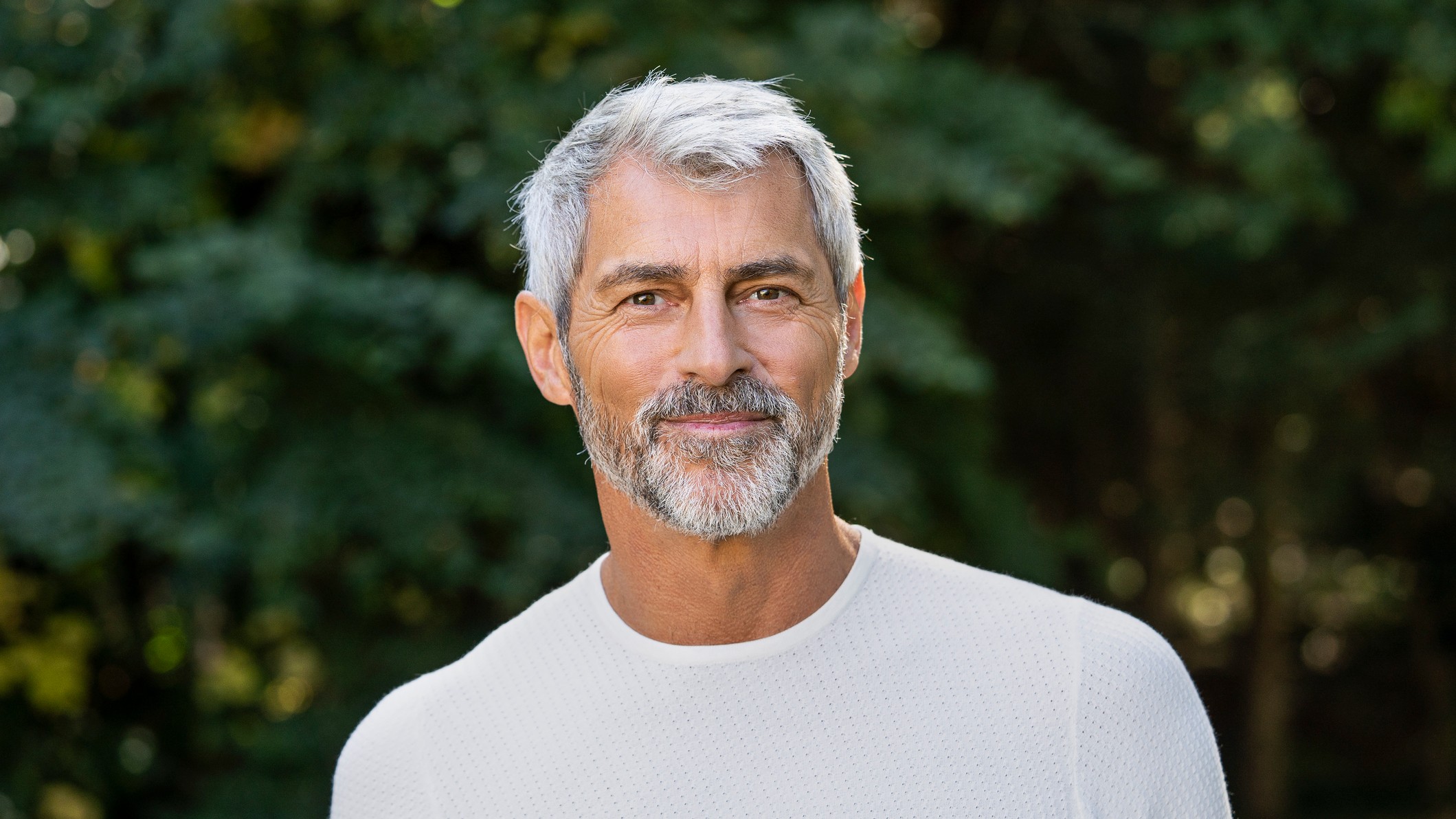 Portrait of smiling mature man standing in backyard.