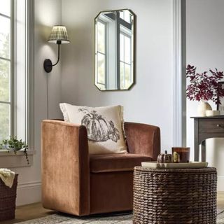 A orange velvet armchair with a white pumpkin pillow