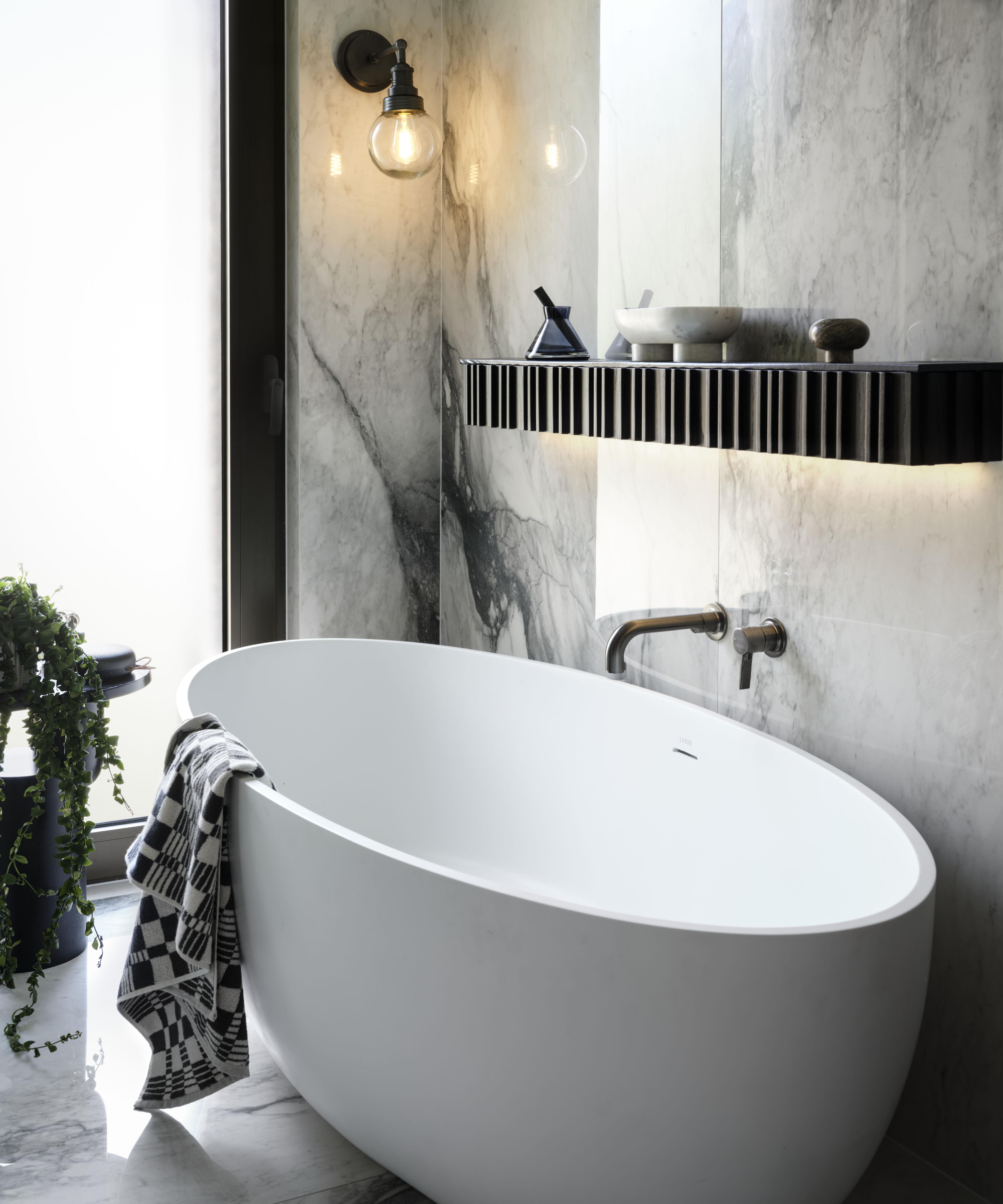 white freestanding bath with black and glass wall light