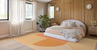 Bedroom with wooden clad walls and a Peach Fuzz pantone color of the year rug beside the bed