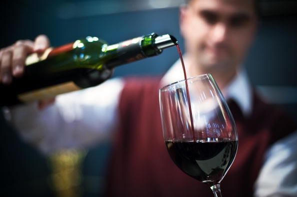 A man pours a glass of red wine.