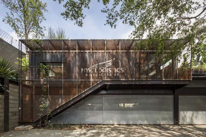 Superlimao create Sao Paulo private gallery. A street level view of a secluded area looking at a two storey building with metal enclosure. 