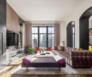 Trevor Noah's Penthouse – Living room with deep purple sofa and large bay windows offering immense city views
