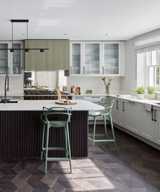 Pale green and brown kitchen, wood chevron floor, white units,mirrored backsplash,