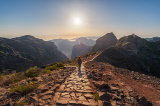 Woman standing and watching the mountains in path that joins Arieiro peak and Ruivo peak in Madeira Island