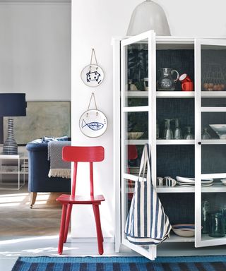 How to style a display cabinet - white glass fronted dresser against white walls with blue and red accessory colour pops