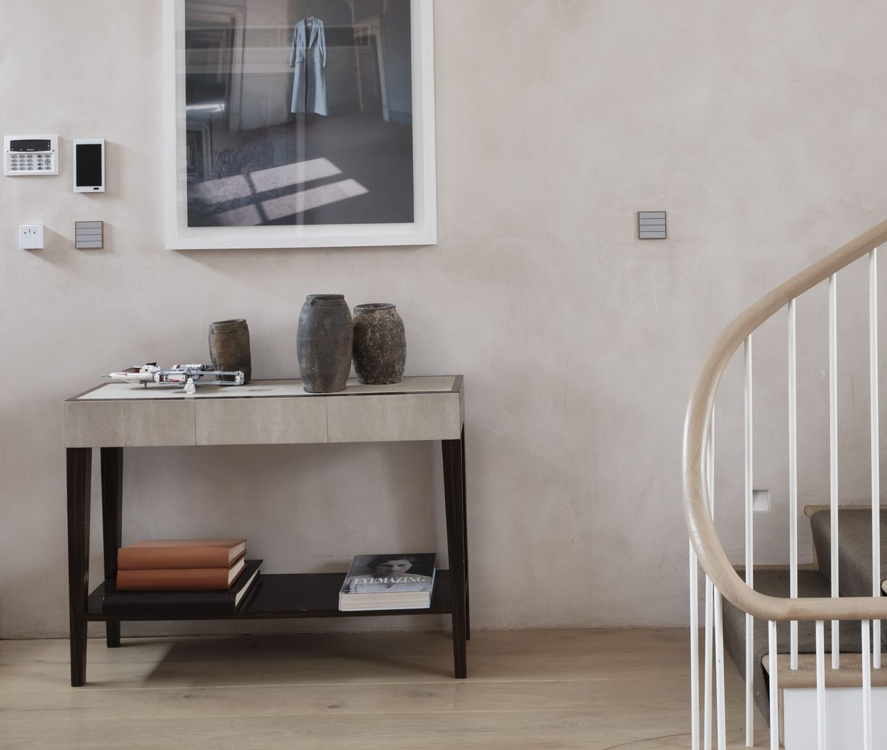 Entryway with spiral staircase, wooden floor, and console table decorated with ceramic vases