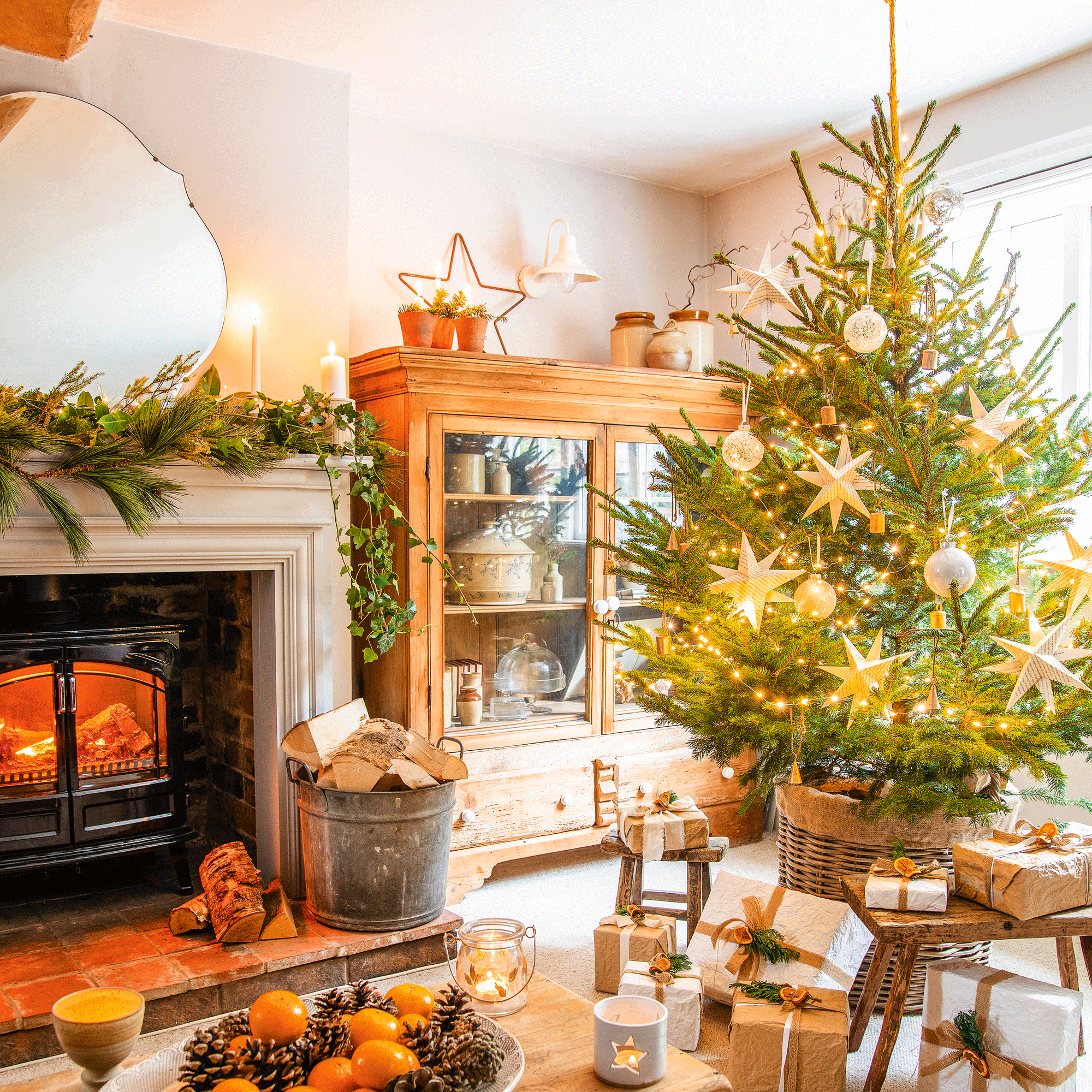 a living room with a fireplace surround with a faux woodburner decorated for Christmas and a Christmas tree