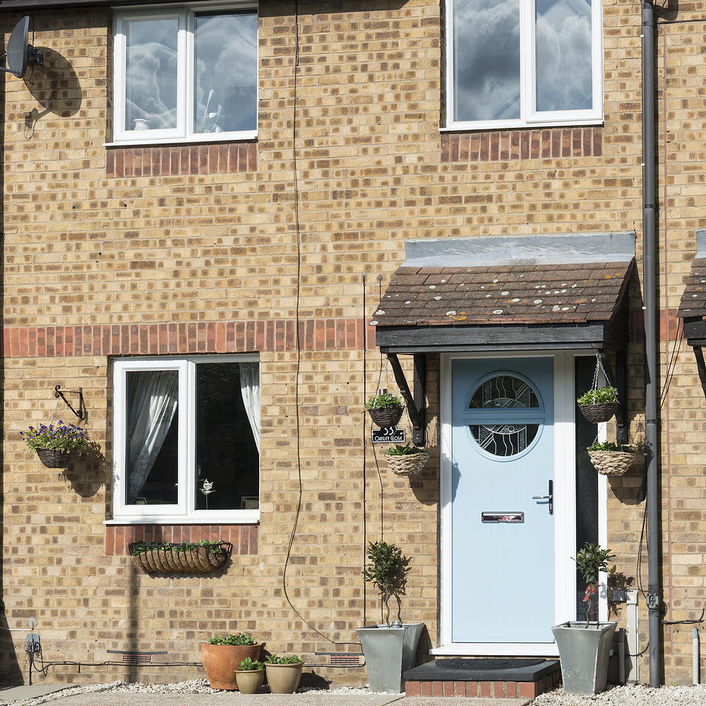 house with brick wall white window door and hanging plants