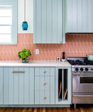 kitchen with light blue cabinets, coral wall tiles and white countertops