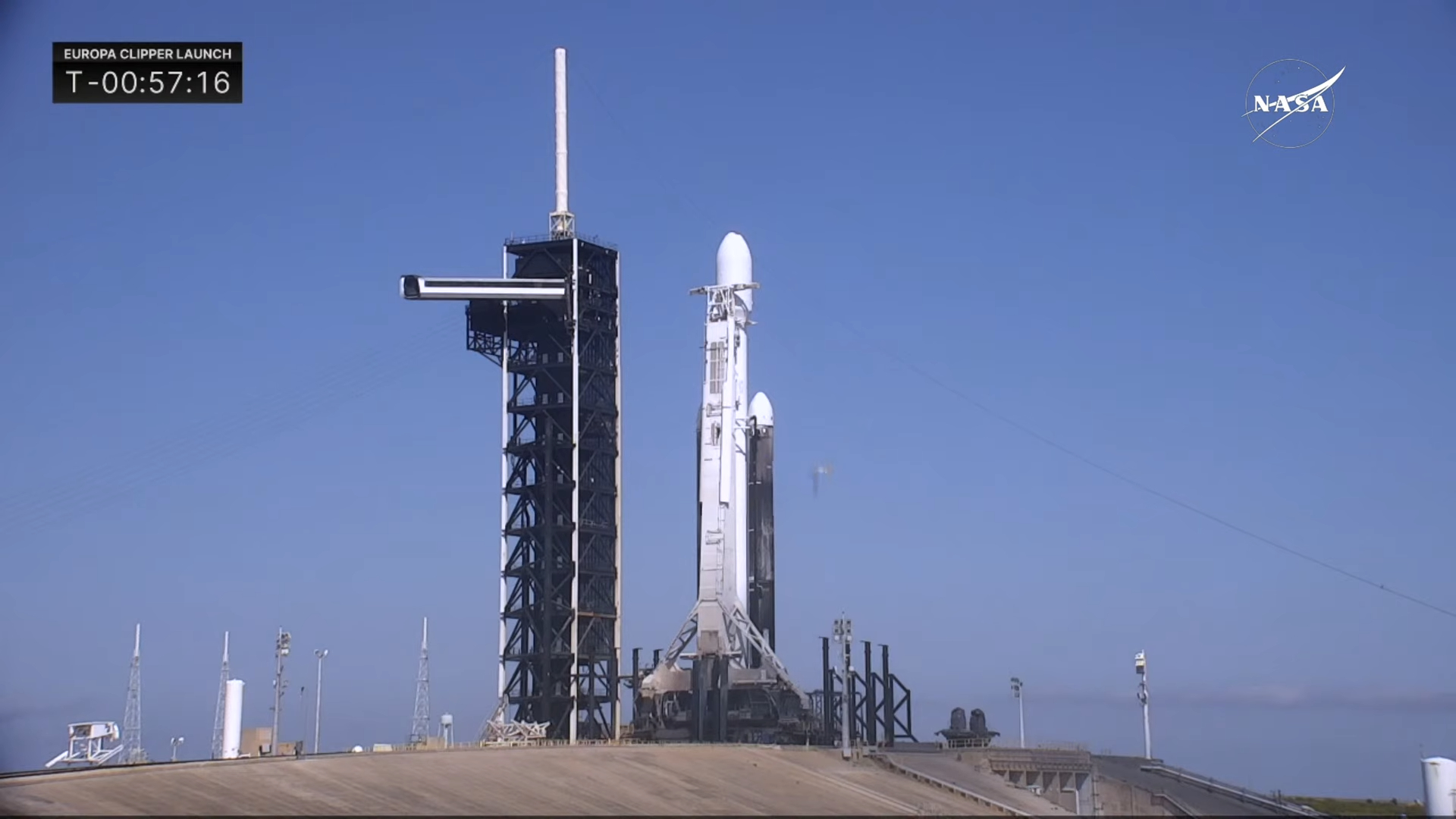 A SpaceX Falcon Heavy rocket on the launch pad at dawn with its reflection in the nearby bay