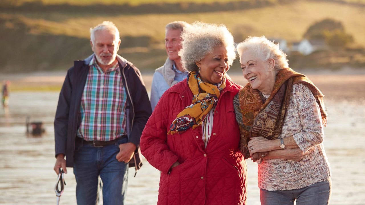 Two senior couples walking and talking along a beach