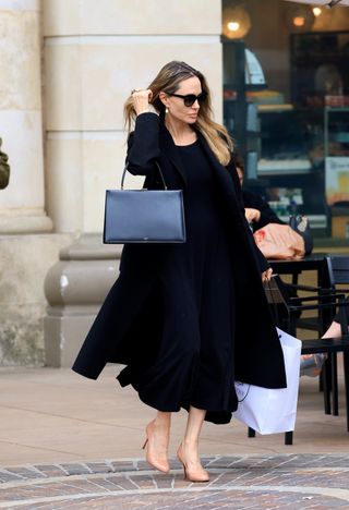 Angelina Jolie walking at The Grove Los Angeles wearing a black dress black bag and Louboutin pumps