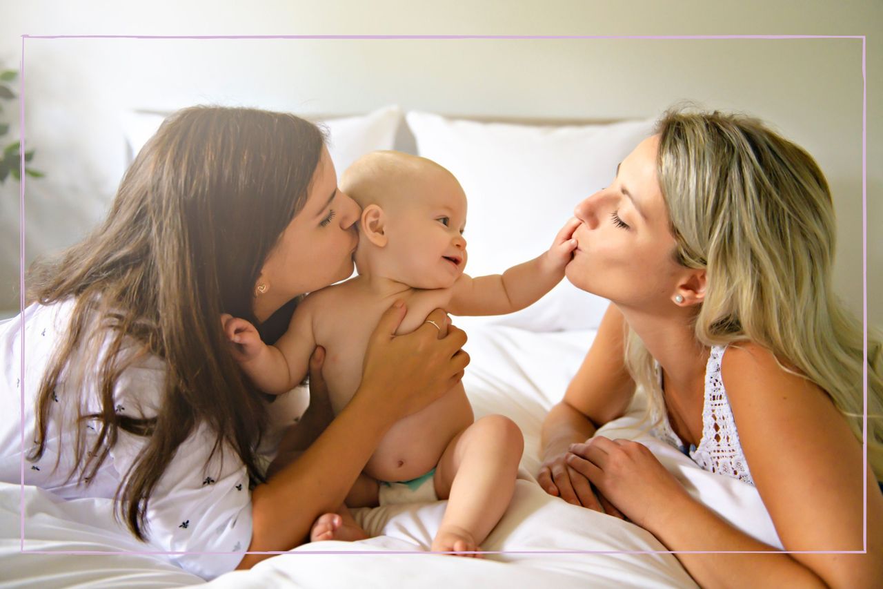 Two mums kissing and playing with their baby