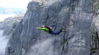 Man BASE jumping off mountain