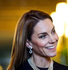 Princess Kate wearing a pearl necklace and sapphire earrings and smiling