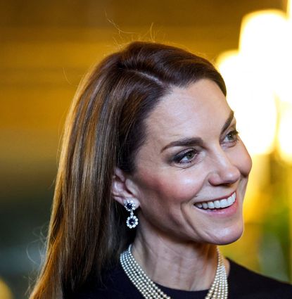 Princess Kate wearing a pearl necklace and sapphire earrings and smiling