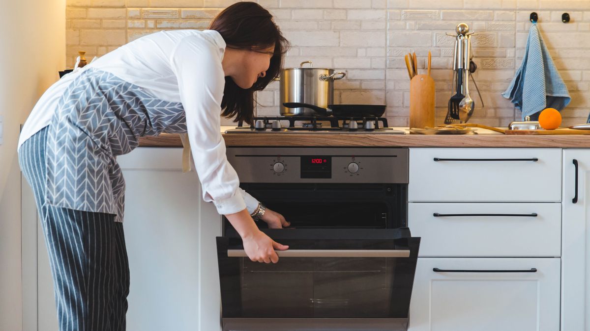 A woman leaning over to open an oven