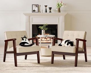 A white living room with a fireplace and two chairs with black and white cats on them