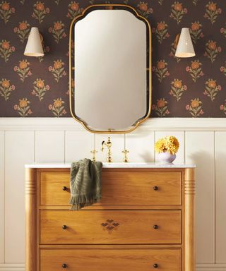 A wood vanity in a wallpapered bathroom