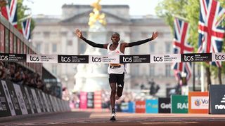 Sebastian Sawe celebrates crossing the line first to win the London Marathon 2025, with Buckingham Palace and the Mall in the background.