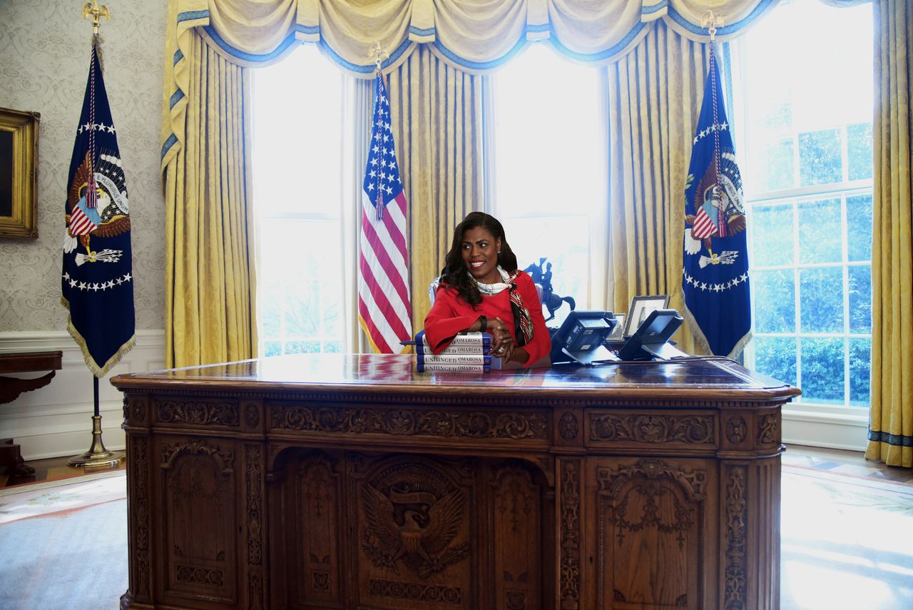 Omarosa Manigault Newman at Oval Office Resolute Desk with a pile of Unhinged memoirs