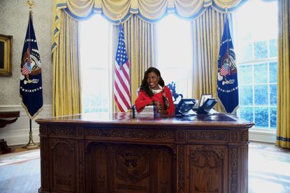 Omarosa Manigault Newman at Oval Office Resolute Desk with a pile of Unhinged memoirs