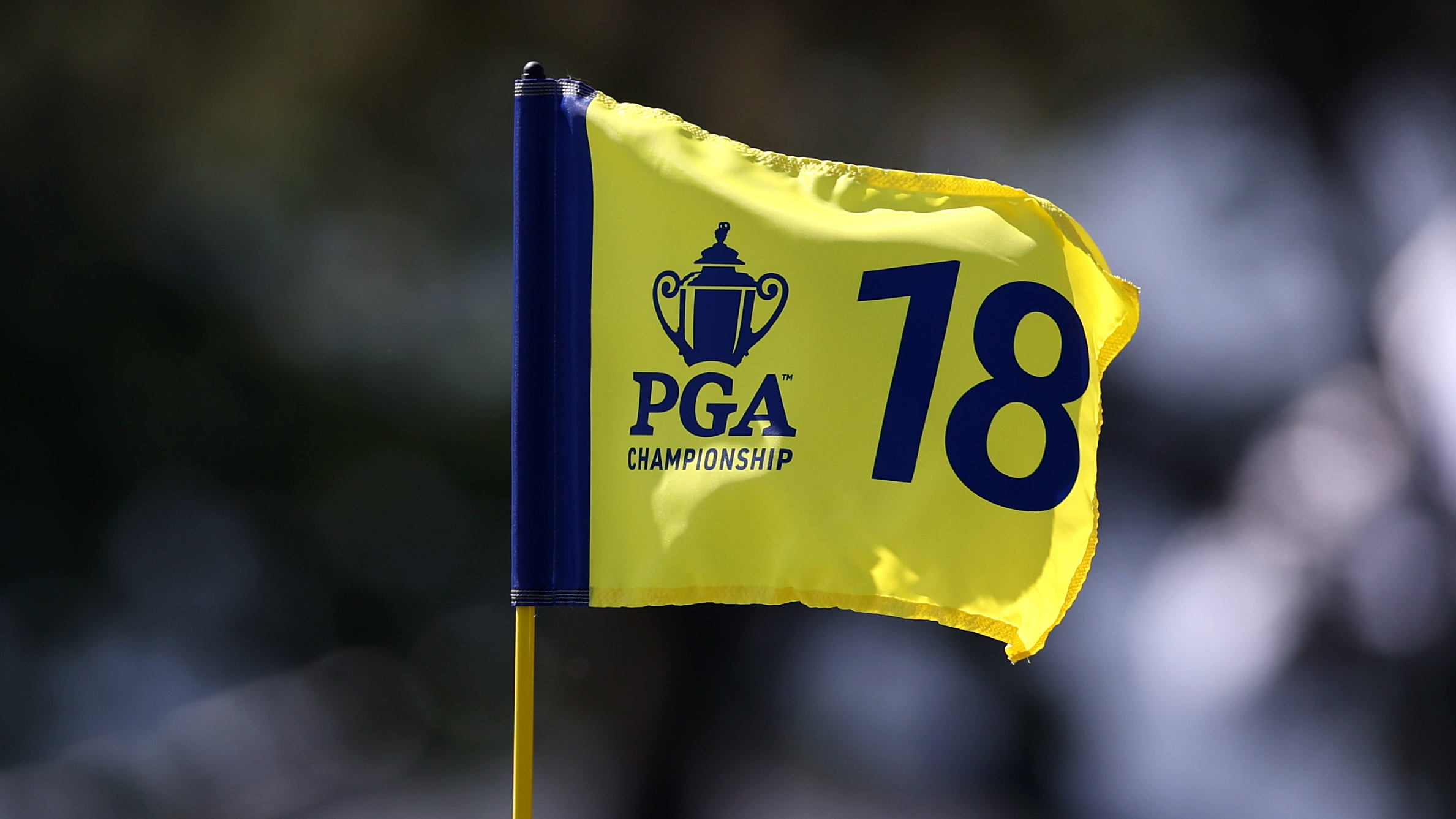 A yellow and blue PGA Championship 18th hole flag blowing in the wind