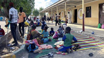 Displaced children in Sudan sit around a school building 