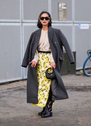 Woman wearing a layered look that incorporates a summer dress, cardigan and coat