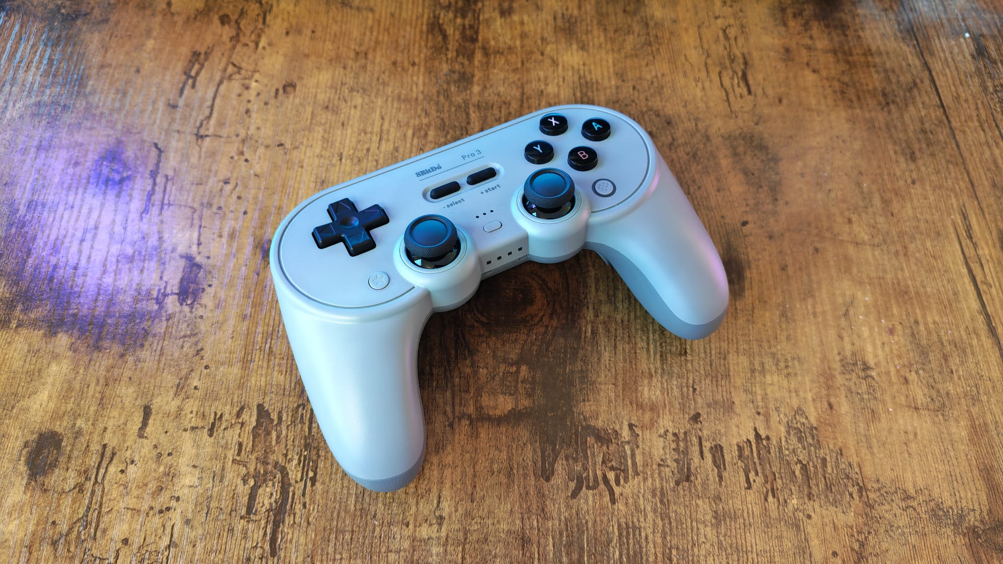 An 8BitDo Pro 3 review image showing the controller on a wooden desktop