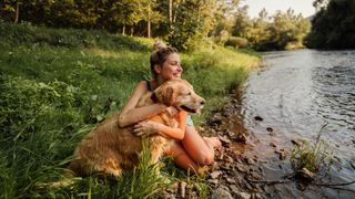 Woman and dog sat by a river