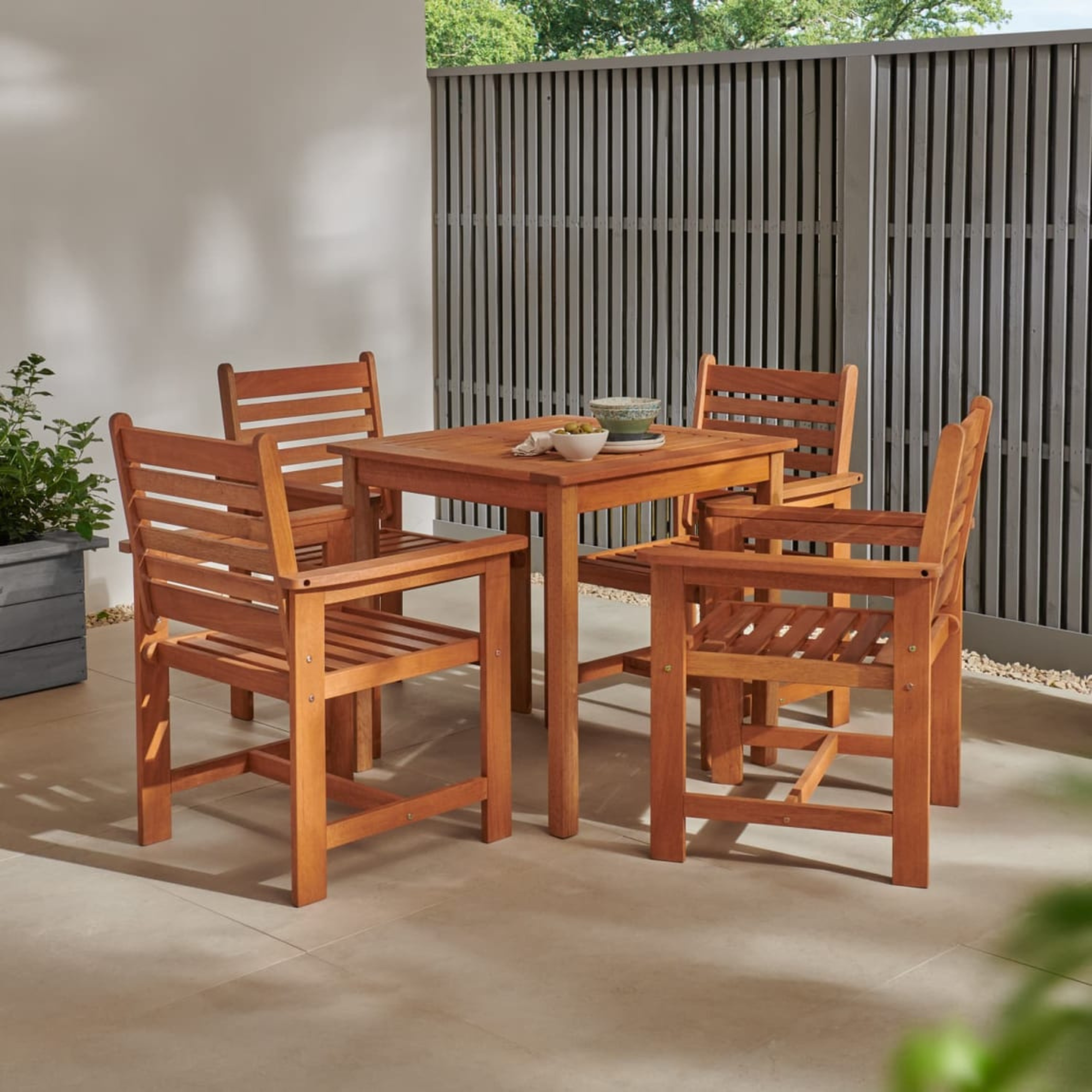 B&amp;amp;M Jakarta dining set on a patio next to grey fence.