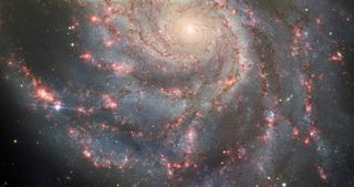 a spiral galaxy with a bright point of light at the end of one of its arms