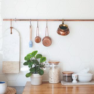 A kitchen with copper measuring cups and a mug hanging on a matching rail