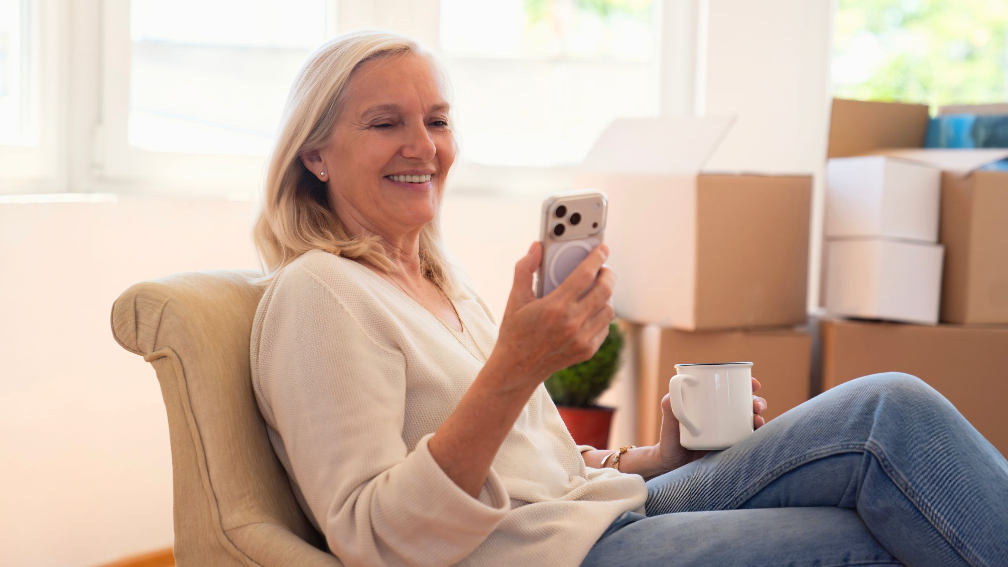 A woman reading a text on her smartphone while drinking a cup of coffee. 