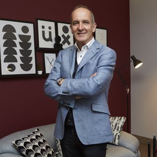 british designer kevin mccloud with frames on red wall