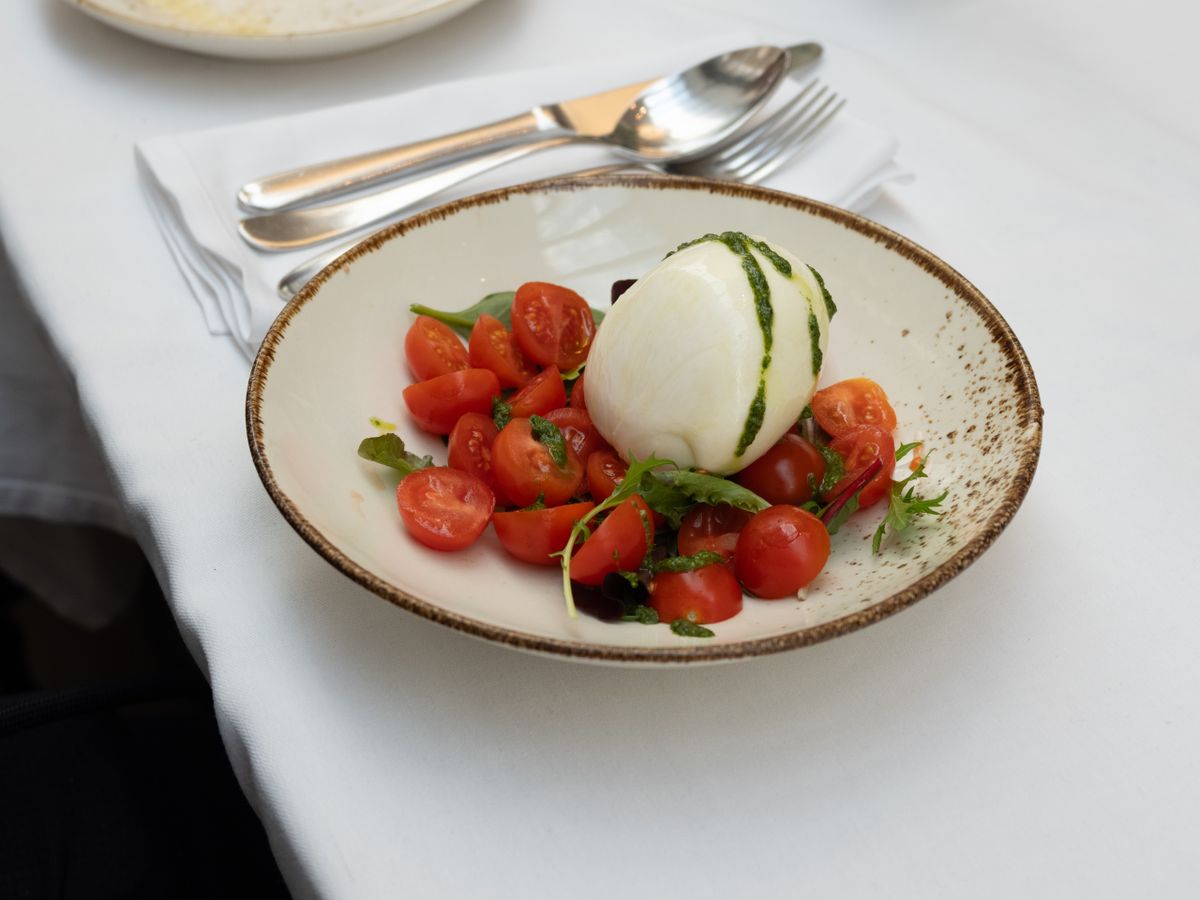 A burrata and tomato dish on a white tablecloth