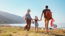 A couple with a little girl walk on the beach.