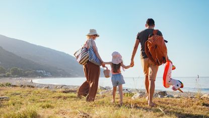 A couple with a little girl walk on the beach.
