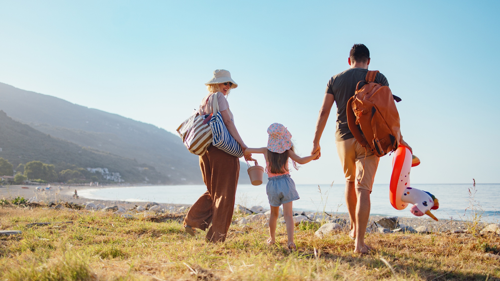 A couple with a little girl walk on the beach.
