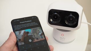Eufy Indoor Cam S350 next to a phone held in a hand