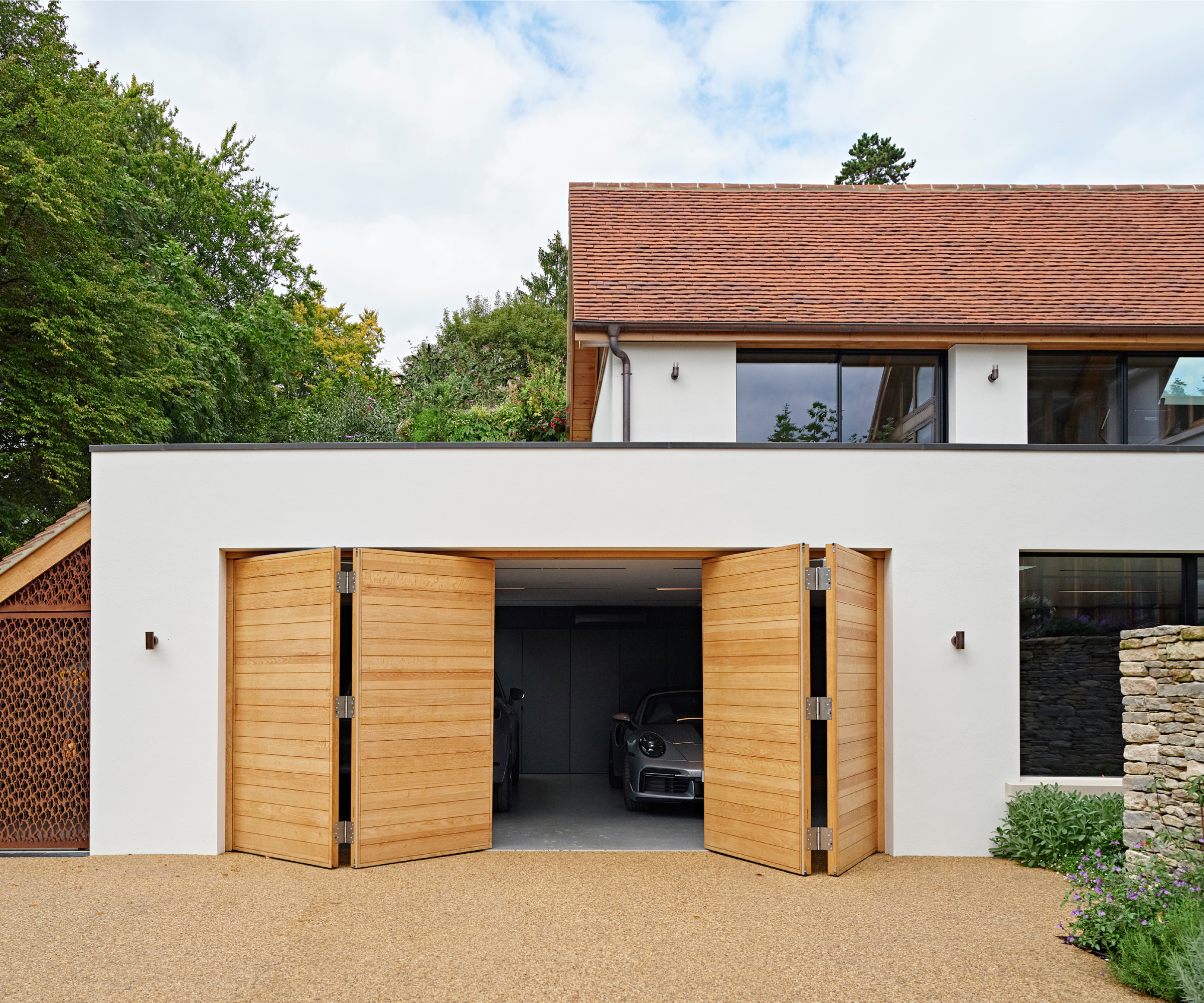 resin driveway in front of wooden double garage doors set into rendered building