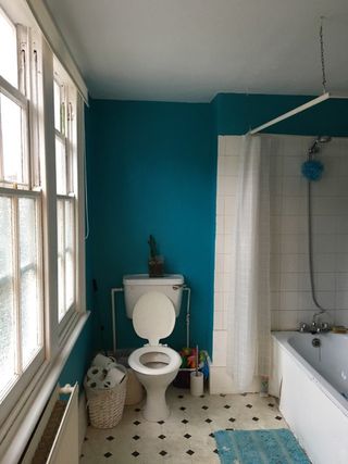 Before shot of bathroom with dark blue walls and white suite