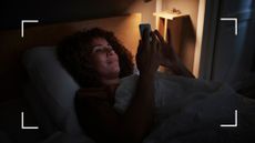 Woman looking at bright light of phone late at night, finding the best noise for sleep