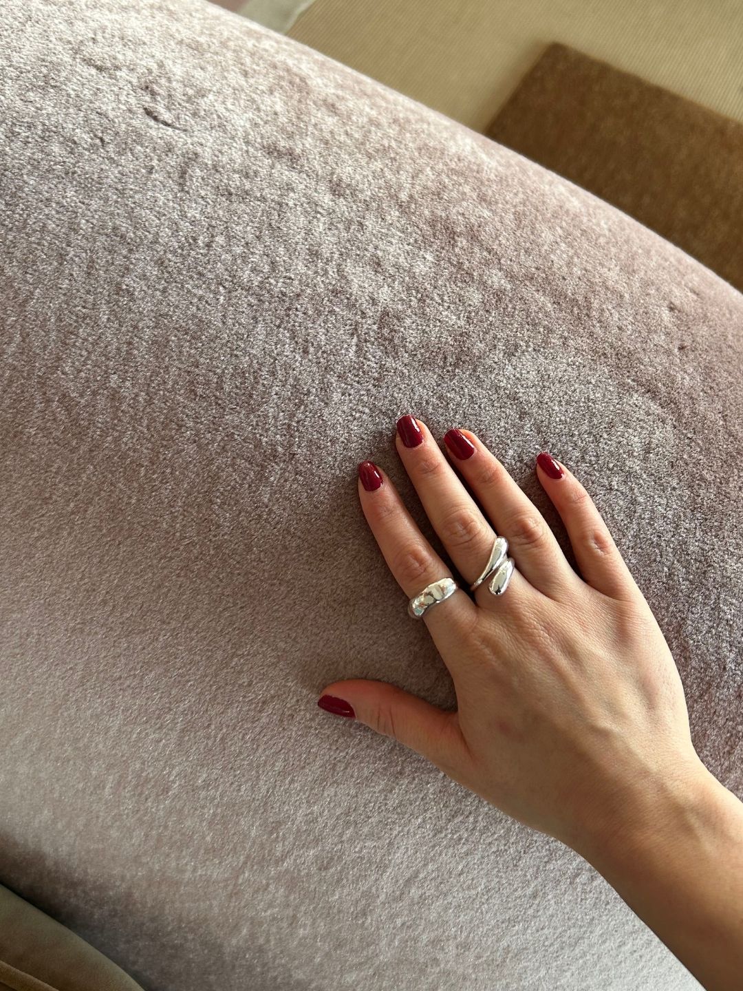 A hand resting on the plush, pale pink Heather Mohair Velvet upholstery of the Lenny sofa, highlighting the fabric's dense pile and sheen.